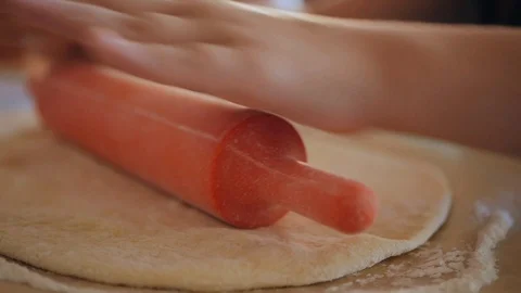 The hands of the chefs roll the raw dough with a rolling pin on the table Stock Footage 95803149
