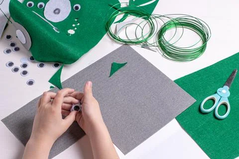 Hands of a child doing homework on making an alien mask. Craft tools, objects Stock Photos