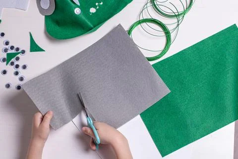 Hands of a child doing homework on making an alien mask. Craft tools, objects Stock Photos