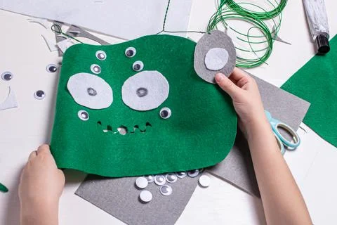 Hands of a child doing homework on making an alien mask. Craft tools, objects Stock Photos
