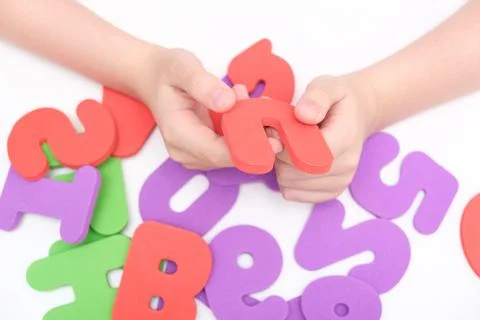 Hands of a child, kid holding colorful numbers during education, learning math Stock Photos