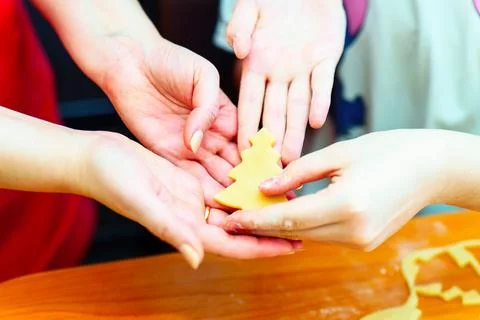 Hands child makes a Christmas tree shape out of dough using a metal mold Stock Photos