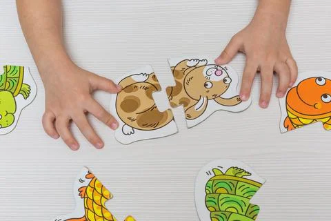 The hands of a child playing with puzzles. Stock Photos