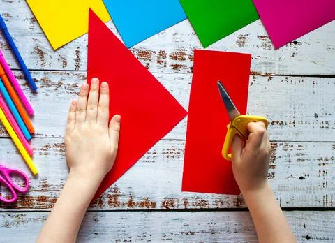 Hands of a child with scissors on the background of colored paper. Stock Photos