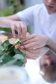 The hands of a child sitting at a table with a mirror surface and playing wit Stock Photos