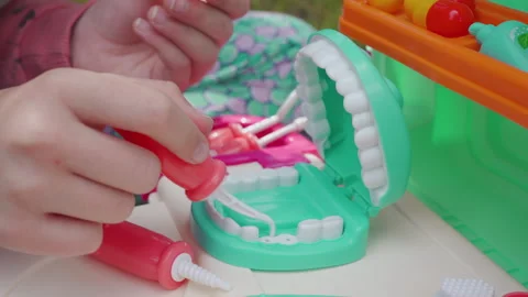 Hands of a child treating teeth on a toy plastic jaw model Видео 341237306