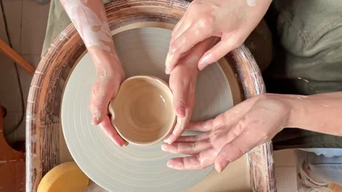 The hands of child work on a potter's wheel and make a pot from clay.  Stock Footage 277788432