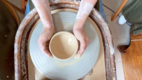 The hands of child work on a potter's wheel and make a pot from clay Stock Footage 277788589