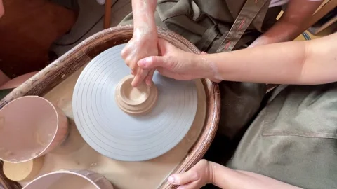 The hands of child work on a potter's wheel and make a pot from clay.  Stock Footage 277793657