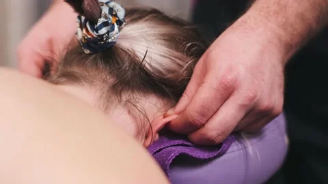 Hands of the chiropractor massage the client's ear Stock Footage 166814063