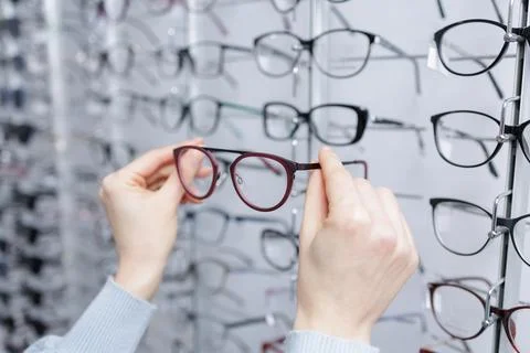Hands choosing eyeglass frames at optician store eyewear shopping and visio.. Stock Photos