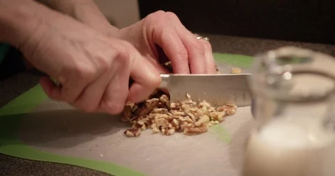 Hands chop pecans and walnuts for baked goods in prep kitchen Stock Footage 123736332