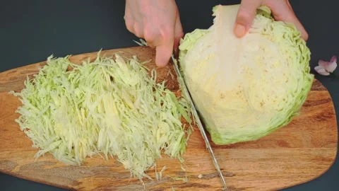 Hands chopping fresh light green cabbage on wooden cutting board indoors Stockbeeldmateriaal 342888950