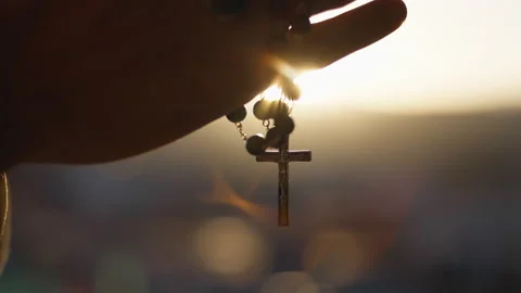 Hands clasp rosary at sunset Stock Footage 237956678