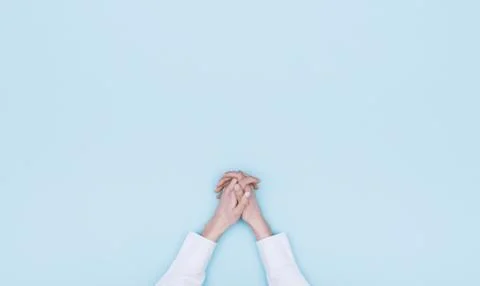Hands clasped on light blue background Stock Photos