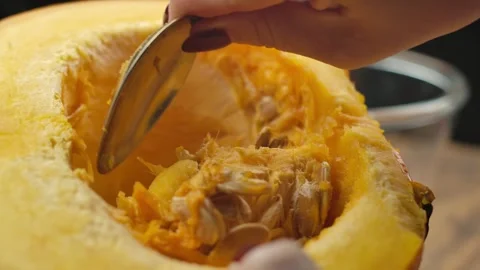 Hands clean a half of a pumpkin from the insides with a spoon Stock Footage 241656443