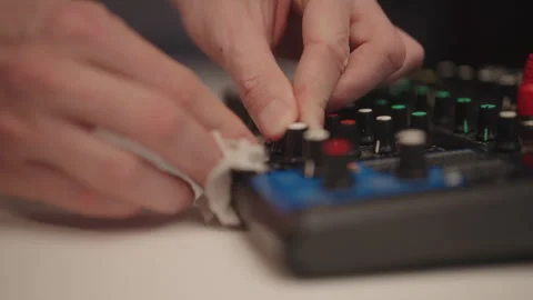 Hands cleaning audio mixing console with microfiber cloth, performing routine Stock Footage 324867462