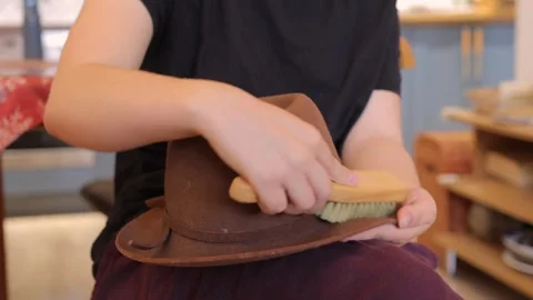 Hands cleaning a brown wide brim hat Vídeos de archivo 337946382