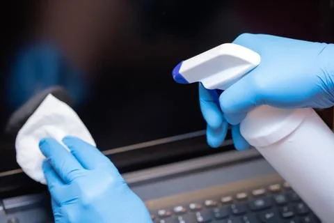 Hands cleaning laptop computer to avoid coronavirus infection Stock Photos