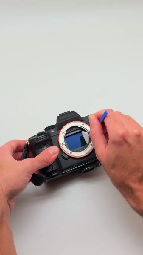 Hands cleaning mirrorless camera image sensor with swab. Stock Footage 323992734