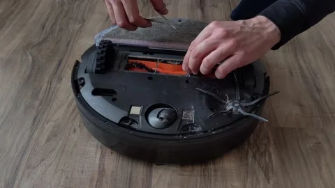 Hands cleaning robot vacuum with tangled long hair in the brush, timelapse Stock Footage 238898894