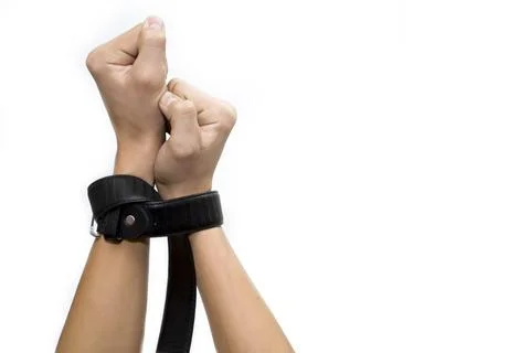 Hands clenched into fists tied with a belt on a white background, slavery to Stock Photos