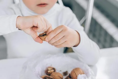 Hands close-up of a boy peeling a nut at the kitchen table Stock Photos