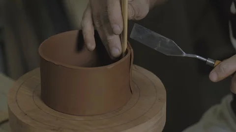 Hands close up cuts off the edges of a clay strip on a wooden platform Видео 119065920