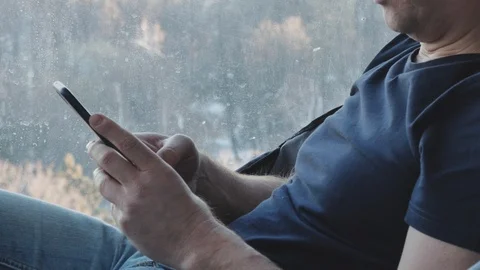 Hands close up. A middle aged man uses a smartphone. He is studying various Video stock 99366003
