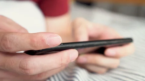 Hands close up playing a mobile game on smartphone at home. Young gamer using Stock Footage 129299405