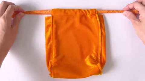 Hands closing drawstring pouch on white tabletop background. Drawstring bag Stock Footage 311364529