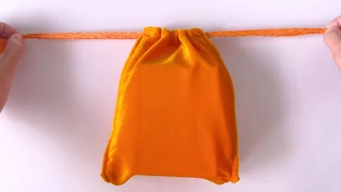 Hands closing velvet drawstring pouch on tabletop. Drawstring bag for make merit Stock Footage 311506942