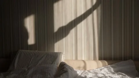 Hands closing window curtain from warm morning light in a bedroom. Blackout Stock Footage 148131563