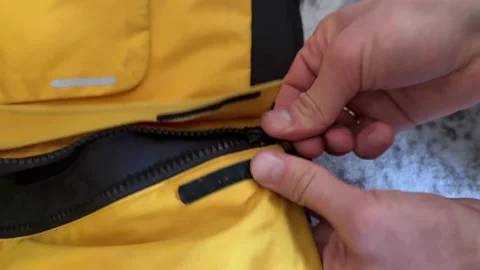 Hands closing zipper on yellow jacket 스톡 동영상 335694728