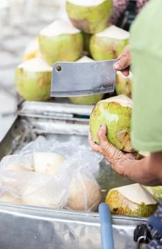 Hands with Coconut and Knife. Preparing Coconut for Drinking Stock Photos