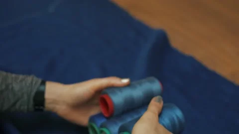 In the hands of a coil of blue thread. Lays threads on blue fabric Video stock 152953396