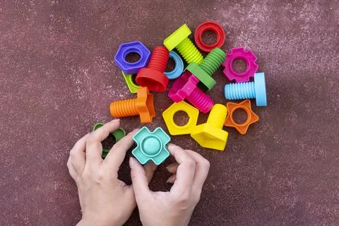 Hands collect educational constructor for children, nuts and bolts in the form Stock Photos