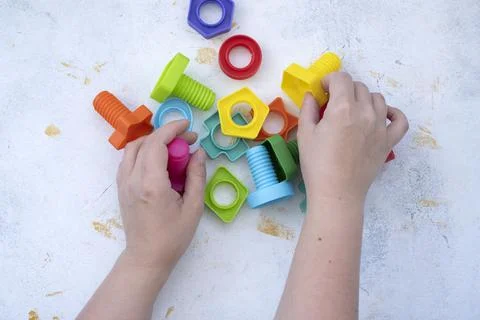 Hands collect educational constructor for children, nuts and bolts in the form Stock Photos