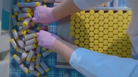 Hands collect plastic tubes with a solution and yellow lids Stock Footage 111608944