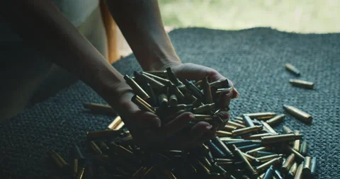 Hands collecting spent bullet shells after shooting session at outdoor range Stock Footage 312221199