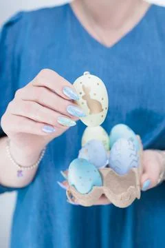 Hands with colored manicure hold Easter eggs. Light yellow, blue and pink color. Stock Photos