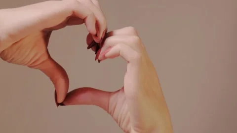Hands complete a heart outline with fingertips, highlighting red nail tips and Stock Footage 319657991