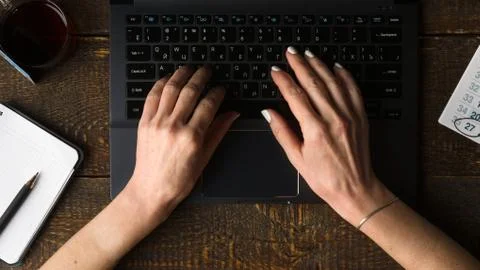 Hands on computer keyboard, notebook and pen view from above Stock Photos