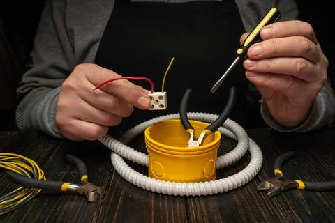 Hands connect wires and tools while working on electrical repairs in a work.. Stock Photos