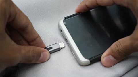 Hands is connecting type c data cable to the phone with a type c port. 스톡 사진