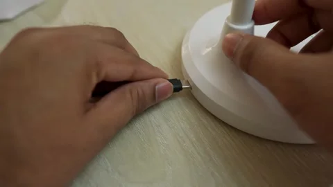 Hands connecting a USB-C cable to a white device on a wooden surface Stock Footage 317737362
