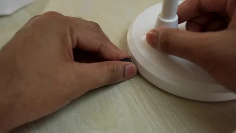 Hands connecting a USB-C cable to a white device on a wooden surface Stock Footage 317737367