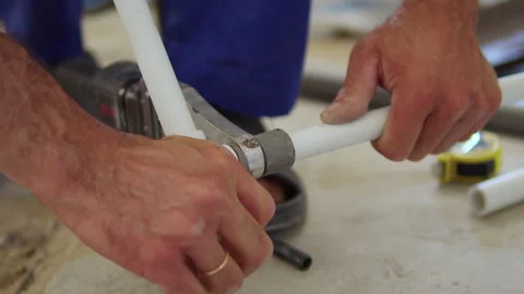 Hands connecting white plastic pipe with metal fitting on floor Stock Footage 312474773