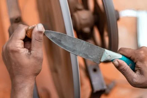 Hands of construction worker sharpens a knife on sanding machine Stock Photos