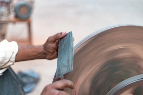 Hands of construction worker sharpens a knife on sanding machine Stock Photos